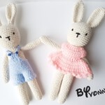 Twee crèmekleurige handgehaakte konijntjes in een blauwe en roze jurk