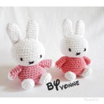 Twee kleine witte handgehaakte konijntjes met roze en rode truien